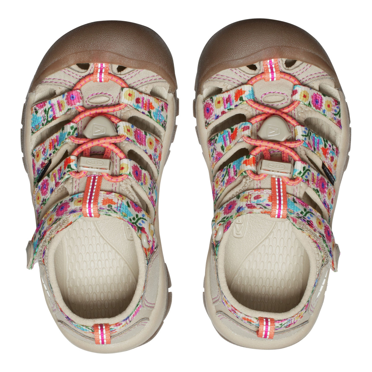 A pair of children's Keen sandals shown from a top-down view on a white background. The sandals feature a beige footbed and toe caps, brown rubber toe protectors, and colorful floral-patterned straps with pink laces.