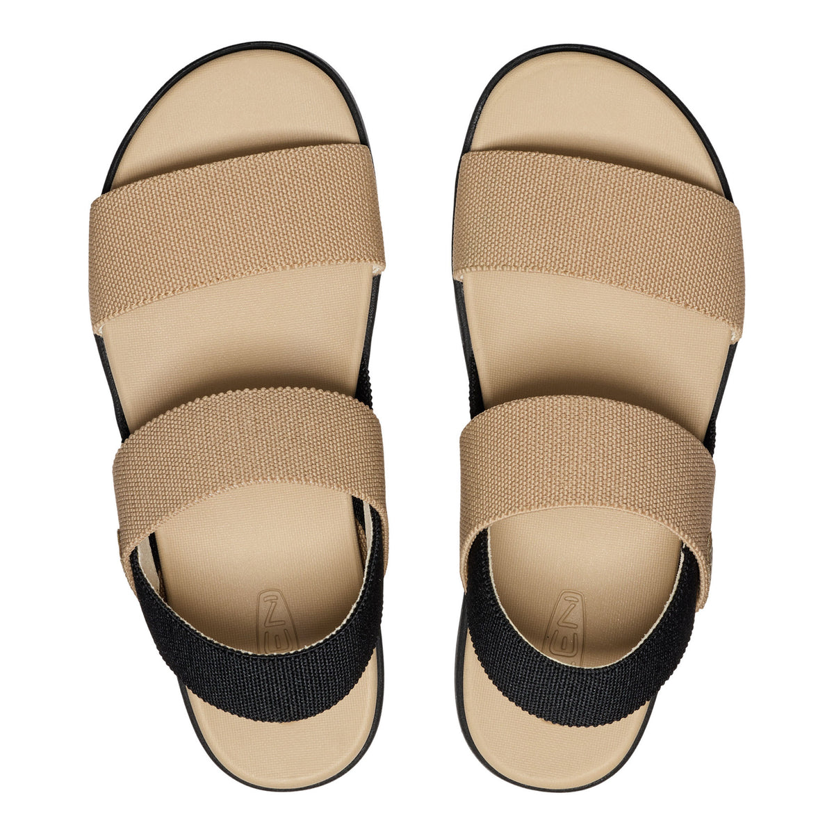 A pair of minimalist slide sandals shown from a top-down view on a white background. The sandals feature a beige woven upper with a black elastic ankle strap and a beige footbed.