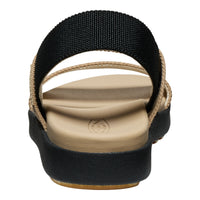 A single women's flat sandal shown from a top-down view on a white background. The sandal features a wide, adjustable black elastic strap, a beige fabric-wrapped edge, a beige contoured footbed, and a thick black platform sole with a tan outsole.