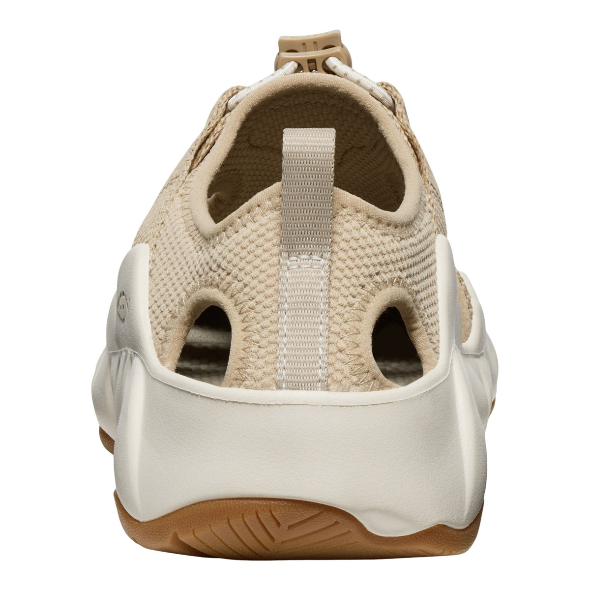 A close-up rear view of a slip-on sneaker in beige and off-white, featuring a textured knit upper, a pull tab, and a thick white midsole with a brown outsole.