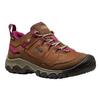 A Keen women's mid-top hiking boot in brown with vibrant magenta accents on the laces, lining, and heel tab, set against a plain white background.