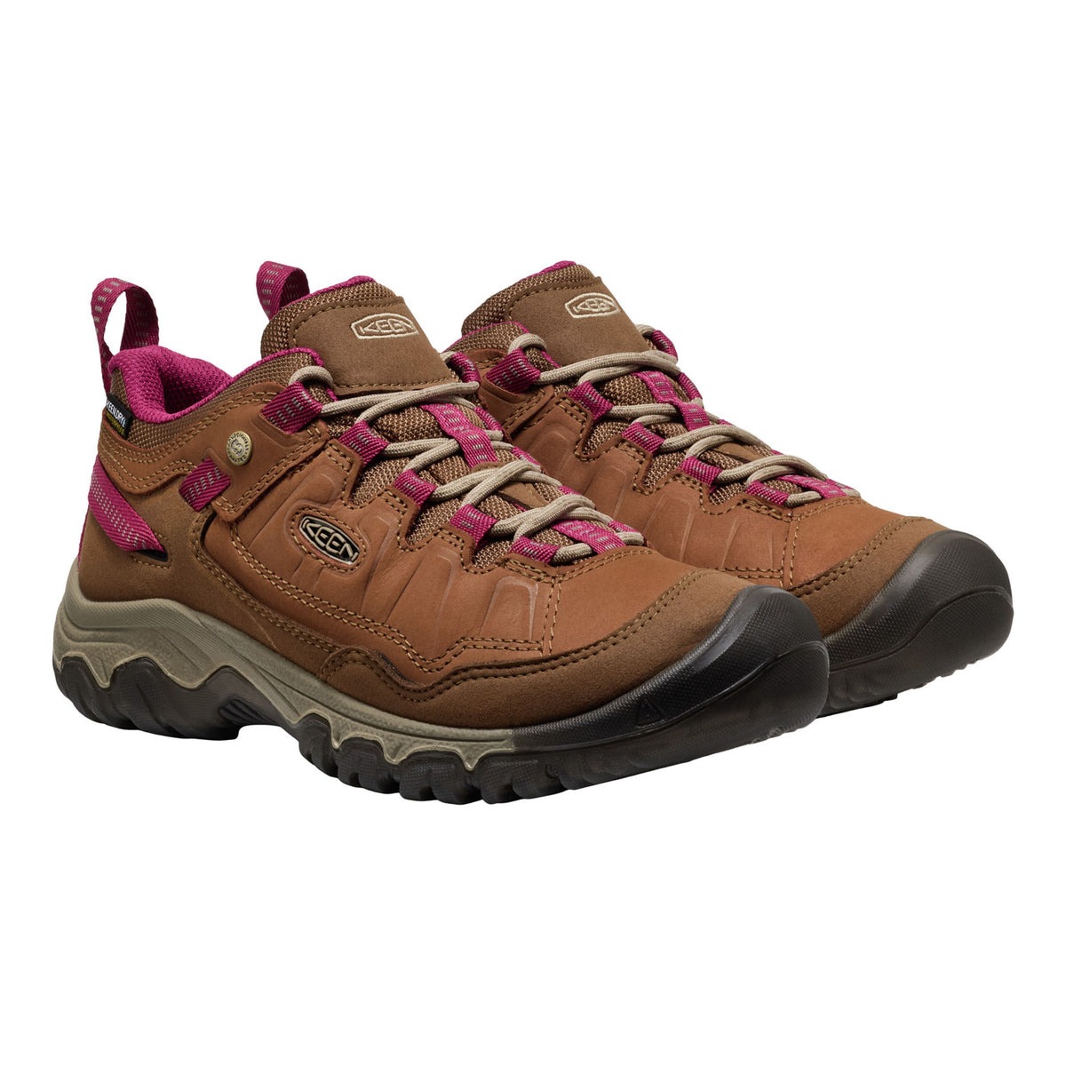 A pair of Keen mid-height hiking boots in brown leather with vibrant magenta-pink laces, pull tabs, and lining, featuring a black and gray rugged sole.