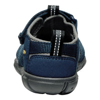 A close-up rear view of a dark blue slip-on shoe with a textured fabric upper, gray lining, and a dark gray sole, shown on a white background.