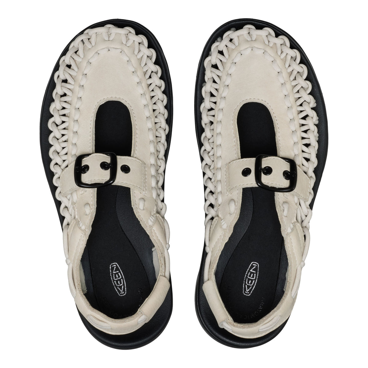 Pair of black and white sandals with decorative straps on a white background