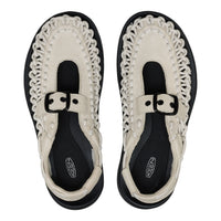 Pair of black and white sandals with decorative straps on a white background