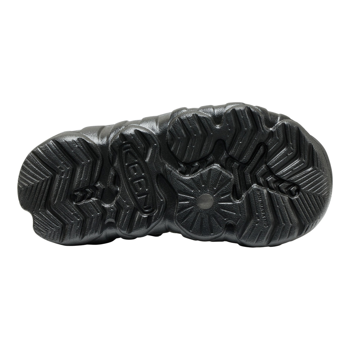 The black textured rubber outsole of a shoe, showing deep tread patterns, photographed from a top-down view on a white background.