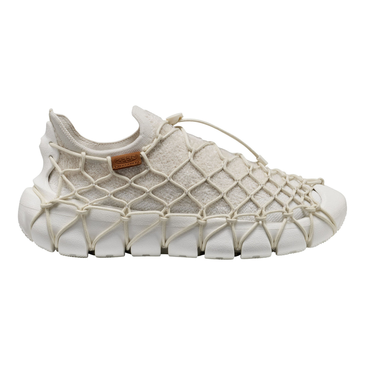 A single slip-on sneaker with a chunky white textured sole and a beige mesh upper wrapped in a crisscross rope net pattern, shown against a plain white background.