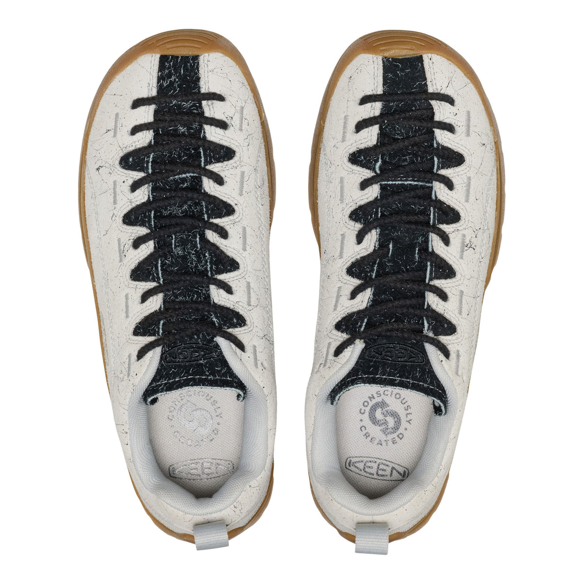 Pair of white sneakers with black laces and brown soles on a white background