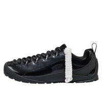 Black sneaker with a white shoelace on a white background