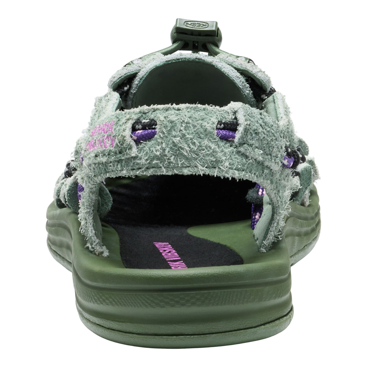 A single green slide sandal with a fuzzy, distressed-texture strap, purple rhinestone accents, and a thick green sole, shown against a plain white background.