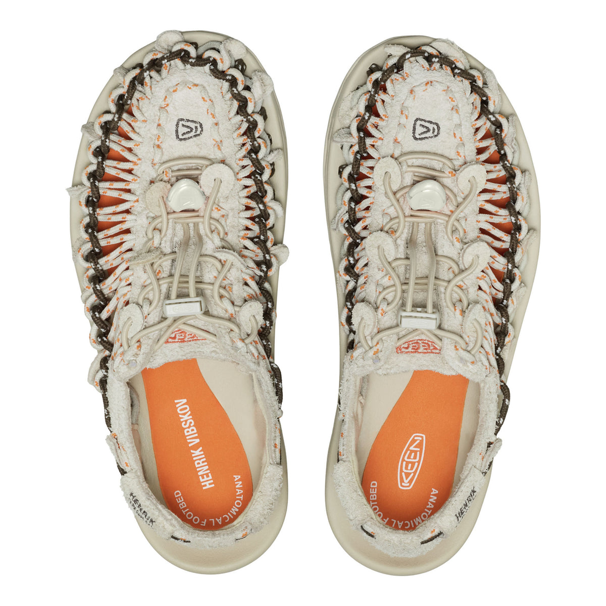A pair of KEEN brand slip-on shoes shown from a top-down view against a white background. The shoes feature a cream-colored woven upper with orange and dark brown accents, and a bright orange insole.