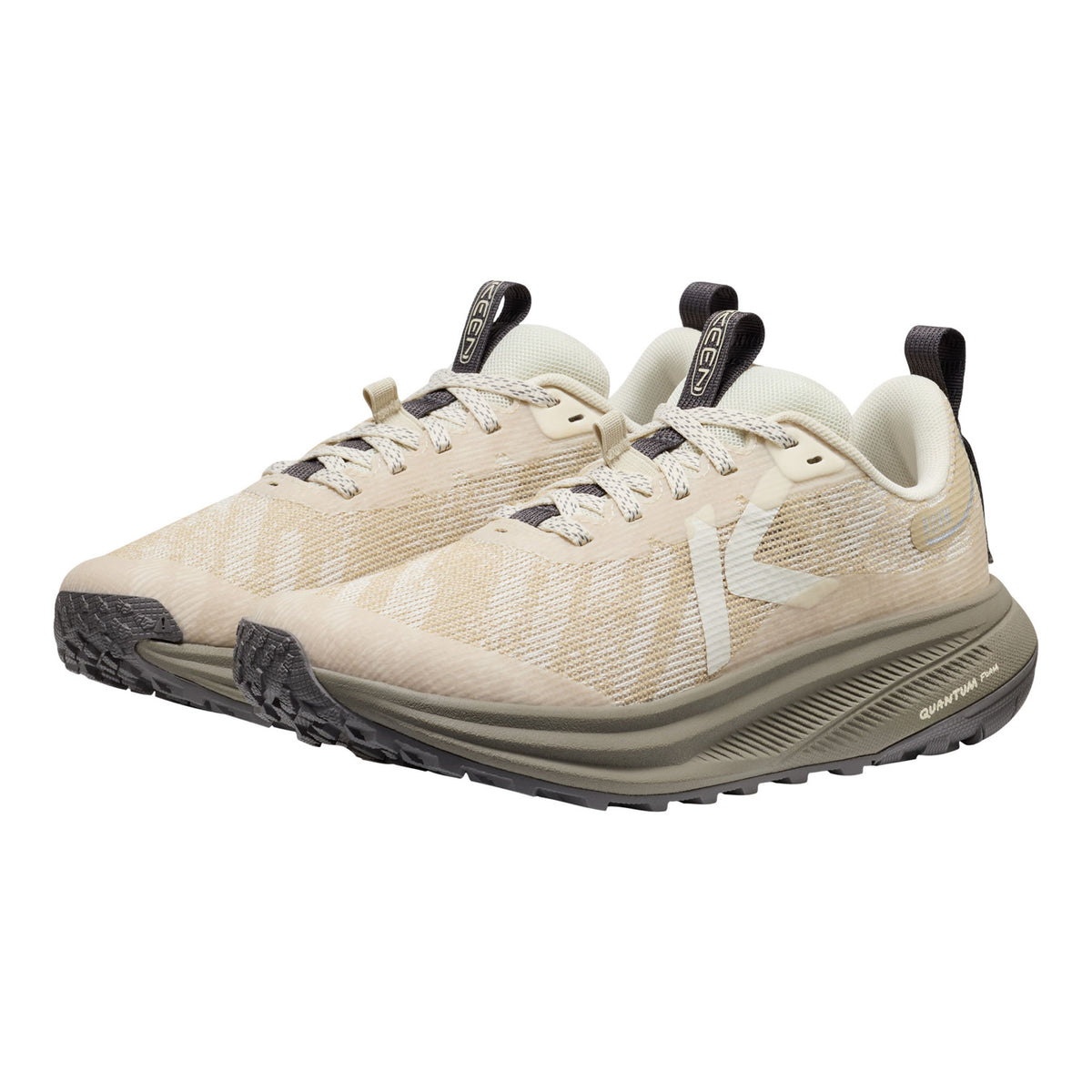 Beige running shoes with black soles on a white background