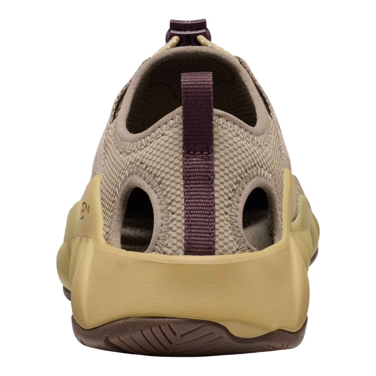 A single slip-on water shoe shown from the rear three-quarter view, featuring a beige knit upper, a tan molded midsole, and a dark brown outsole with a dark purple pull tab.
