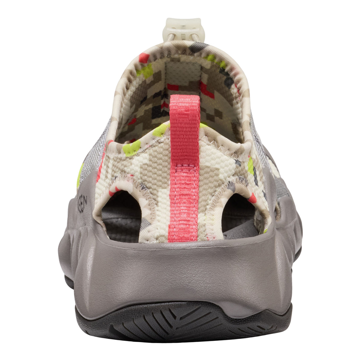 A single shoe shown from the rear, featuring a gray molded sole, a pink pull tab, and a patterned upper in beige, green, and red.