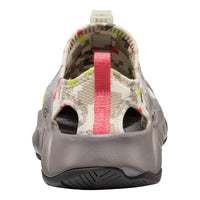 A single shoe shown from the rear, featuring a gray molded sole, a pink pull tab, and a patterned upper in beige, green, and red.