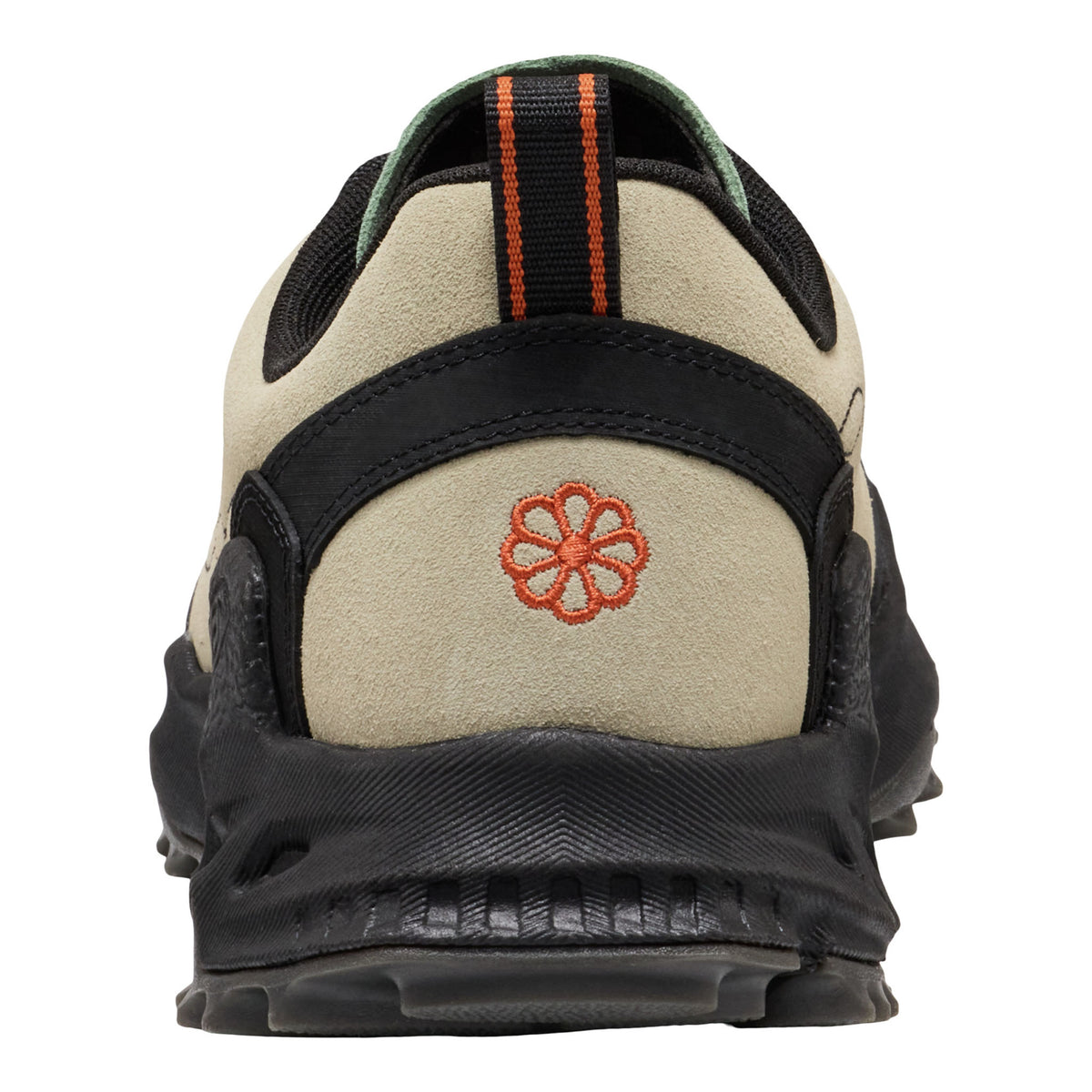 Close-up rear view of a sneaker in beige suede and black synthetic materials, featuring an orange embroidered flower logo on the heel and a black pull tab with orange stripes.