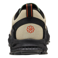 Close-up rear view of a sneaker in beige suede and black synthetic materials, featuring an orange embroidered flower logo on the heel and a black pull tab with orange stripes.