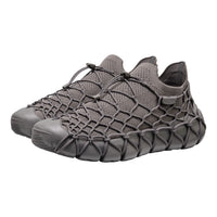 A pair of dark gray slip-on mesh sneakers with a distinctive webbed, snake-like strap pattern across the upper and thick textured soles, shown against a plain white background.