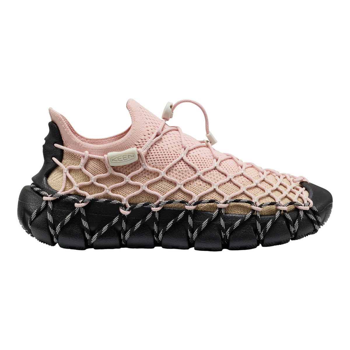 A Keen brand slip-on shoe featuring a light pink mesh upper, a beige woven overlay, and a chunky black textured sole with white stitching.