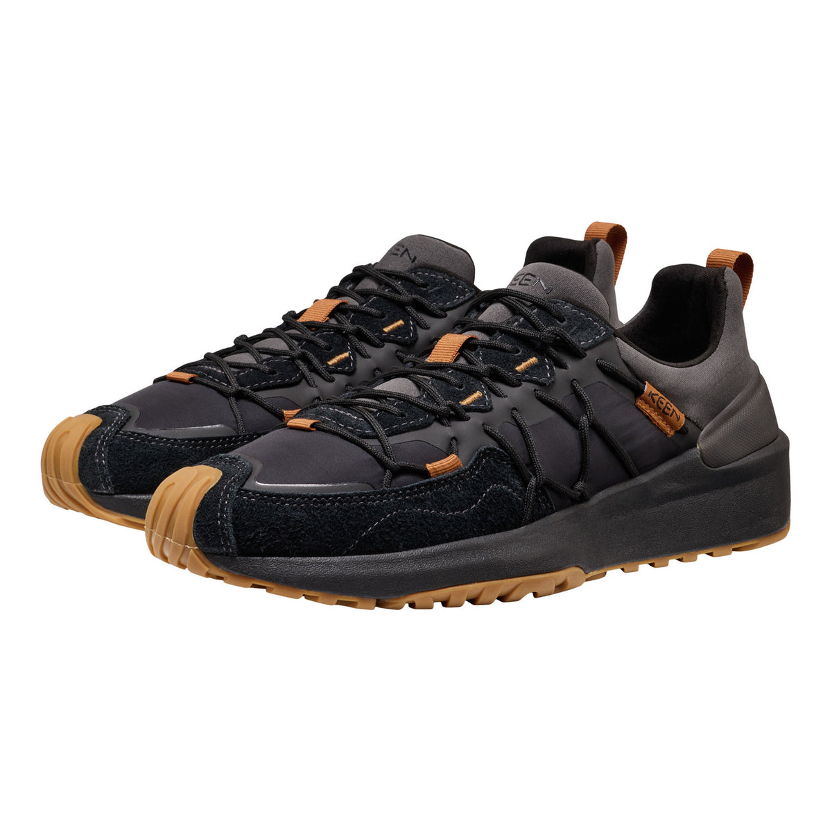 A pair of black and dark gray outdoor sneakers with tan accents on the toe caps, laces, and heel pulls, shown against a plain white background.