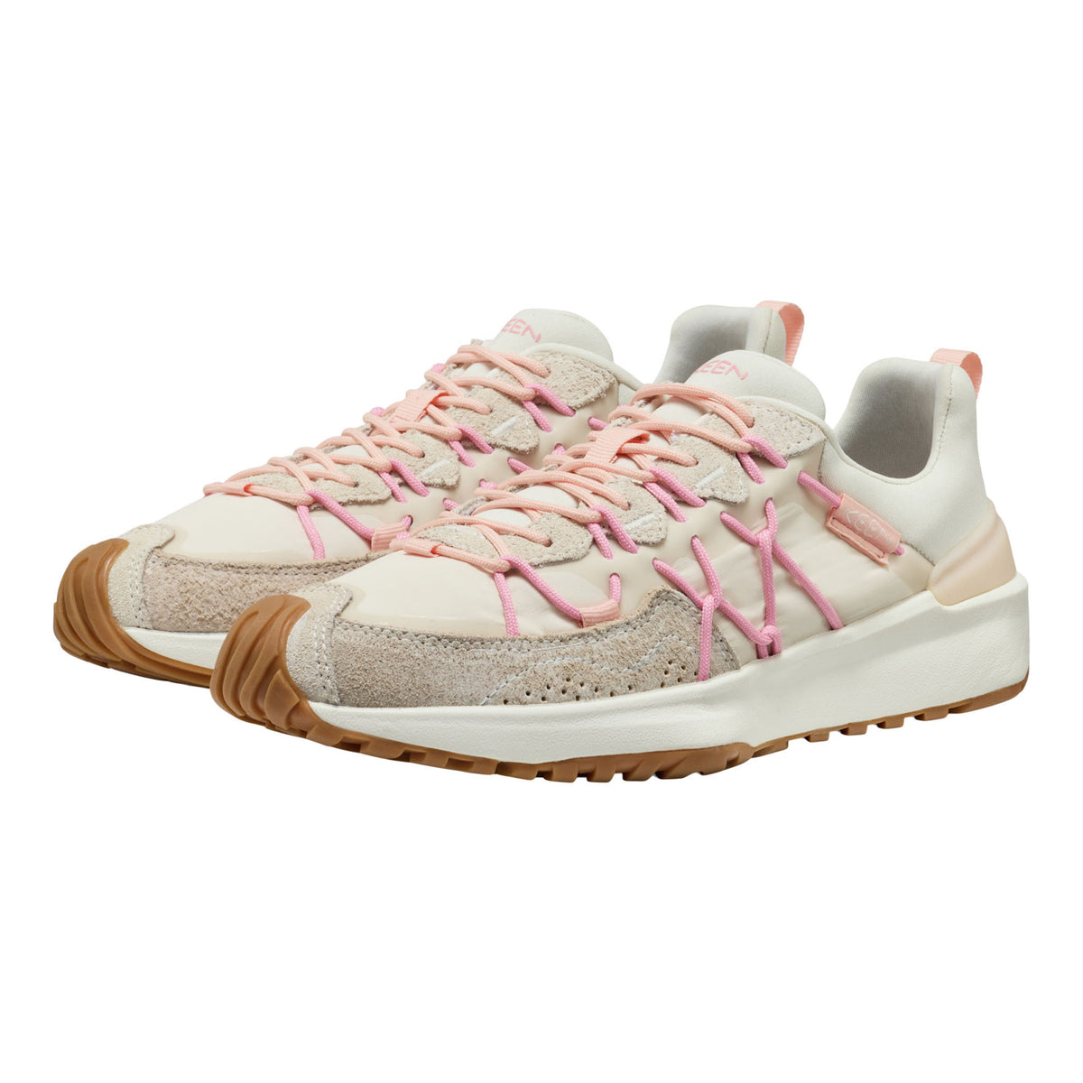 A pair of low-top sneakers in off-white and beige suede/mesh with prominent pink laces and pull tabs, and a brown gum sole, shown on a plain white background.