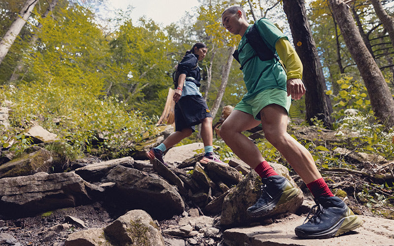 Two people hiking on a rocky trail in a forest