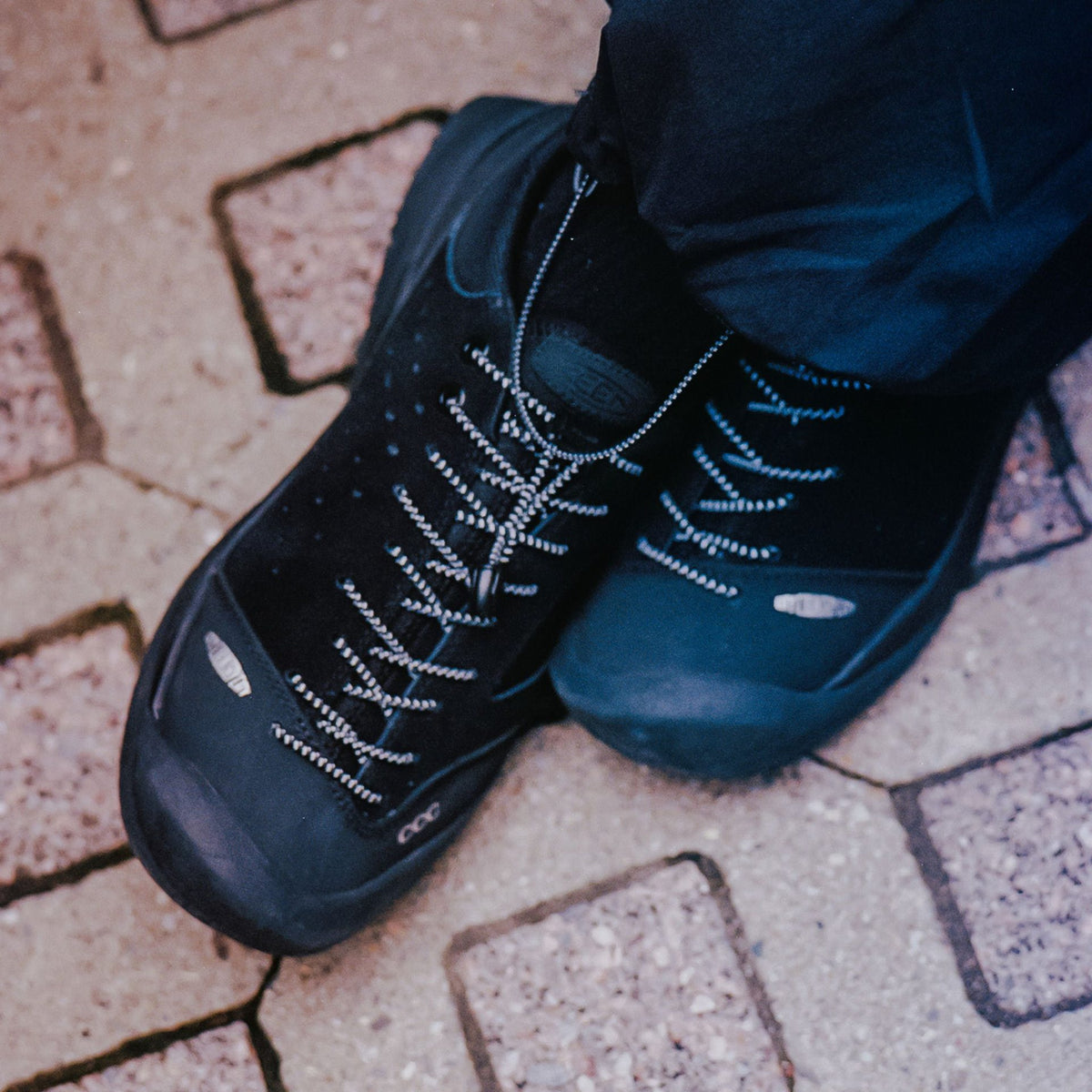 Black sneakers worn on a paved surface