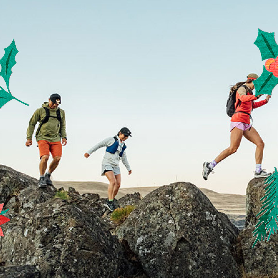 Three people hiking on rocky terrain with a clear sky.
