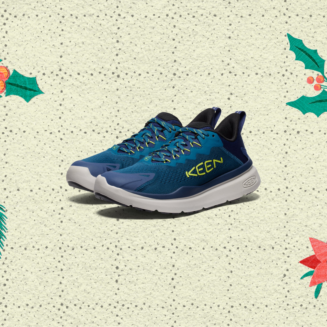Blue KEEN running shoes on a textured beige background with holly leaves and berries.