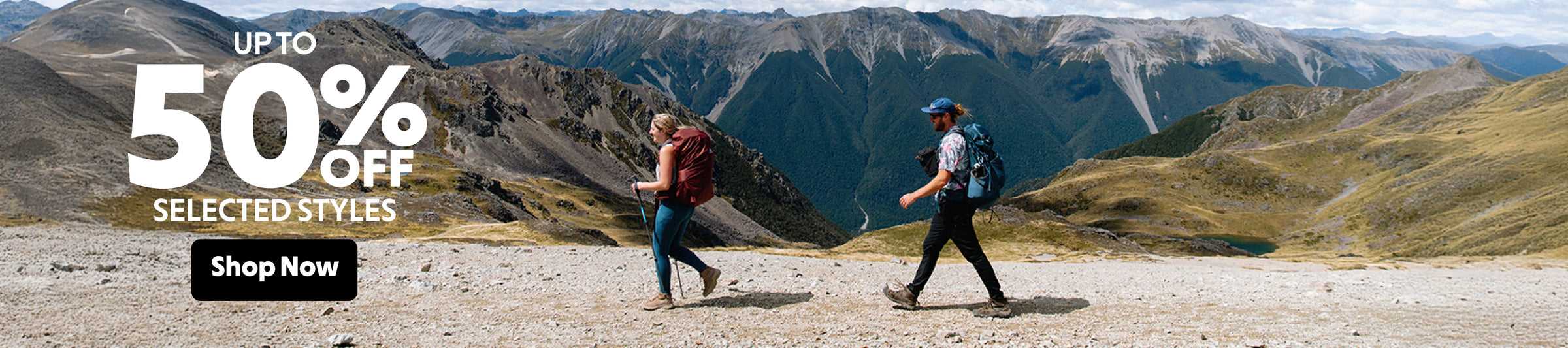 Two hikers on a mountain trail with promotional text overlay for 50% off selected styles.