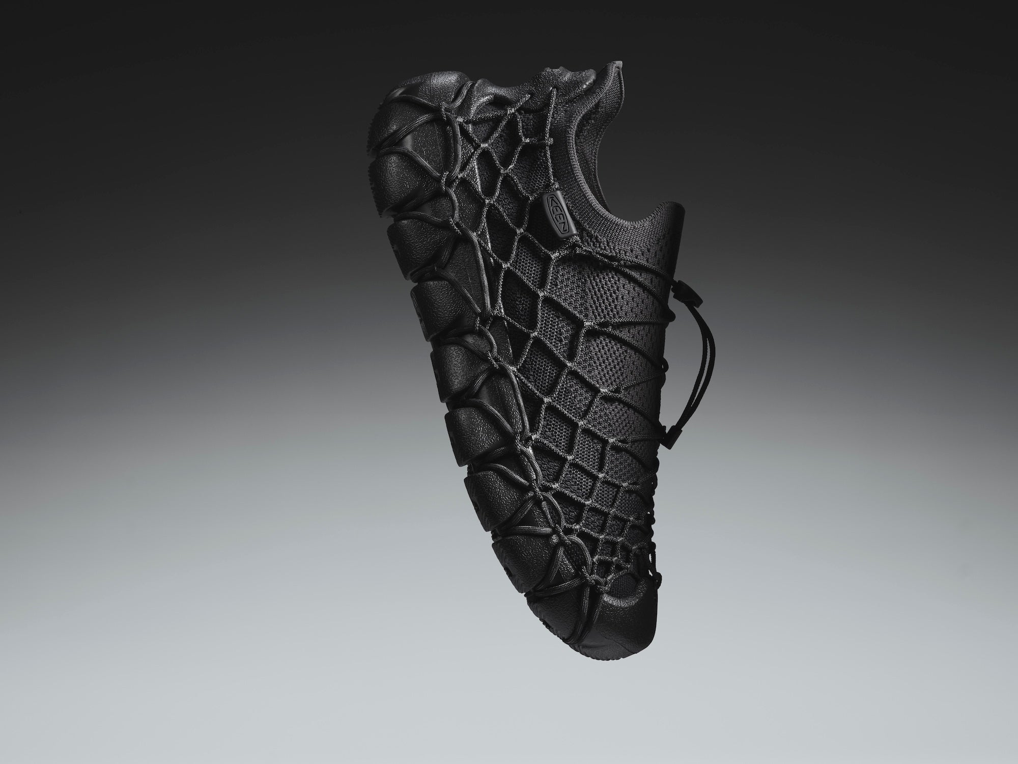 Black textured object resembling a shoe on a gradient gray background