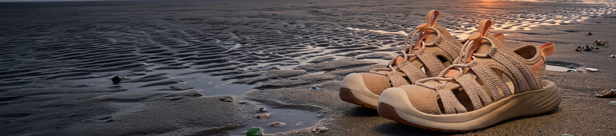 Pair of beige sandals on a beach with waves in the background